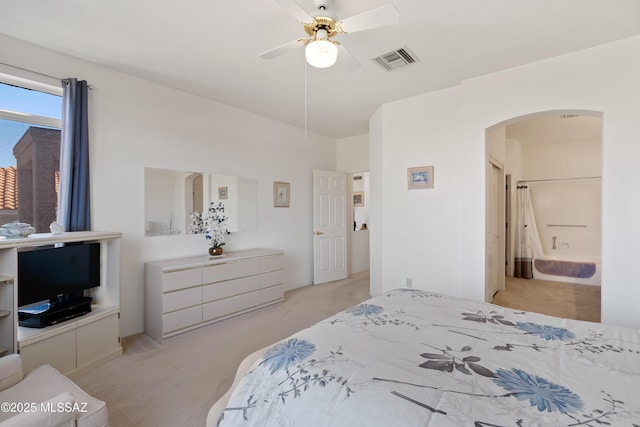 bedroom featuring light carpet, ceiling fan, visible vents, and arched walkways