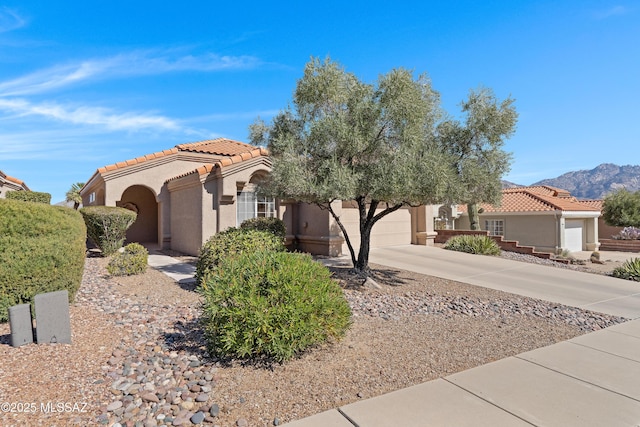 view of front of property featuring a tile roof, stucco siding, an attached garage, a mountain view, and driveway