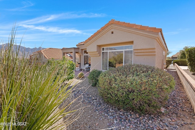 mediterranean / spanish-style home featuring a mountain view, fence, a tiled roof, stucco siding, and a patio area