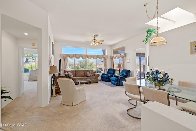 living area featuring light carpet, a healthy amount of sunlight, visible vents, and arched walkways