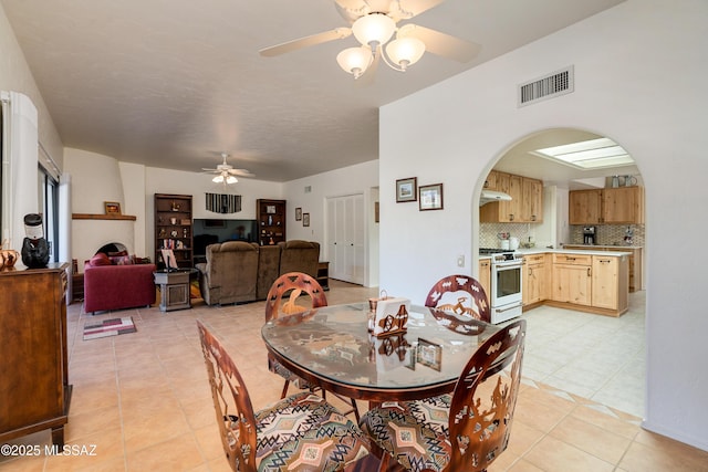 dining area featuring arched walkways, visible vents, ceiling fan, and light tile patterned floors