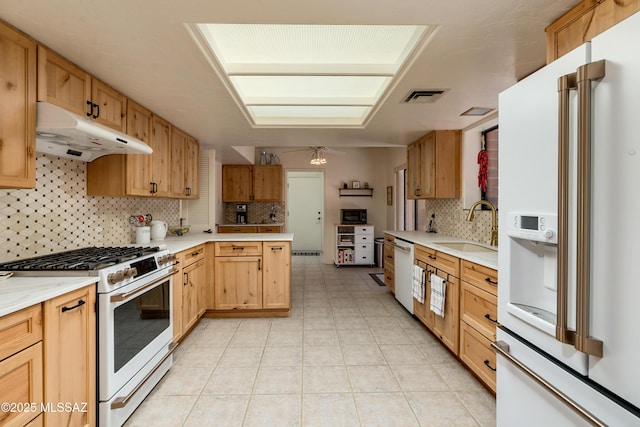 kitchen with white appliances, visible vents, light countertops, under cabinet range hood, and a sink