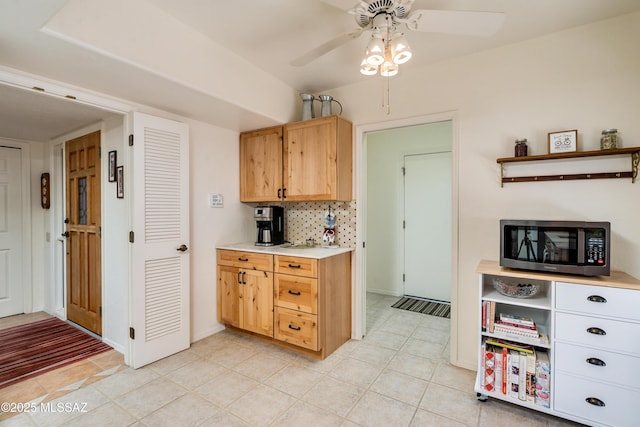 kitchen with light tile patterned floors, a ceiling fan, light countertops, decorative backsplash, and stainless steel microwave