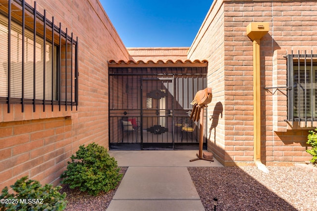 entrance to property with a gate, a tile roof, and brick siding