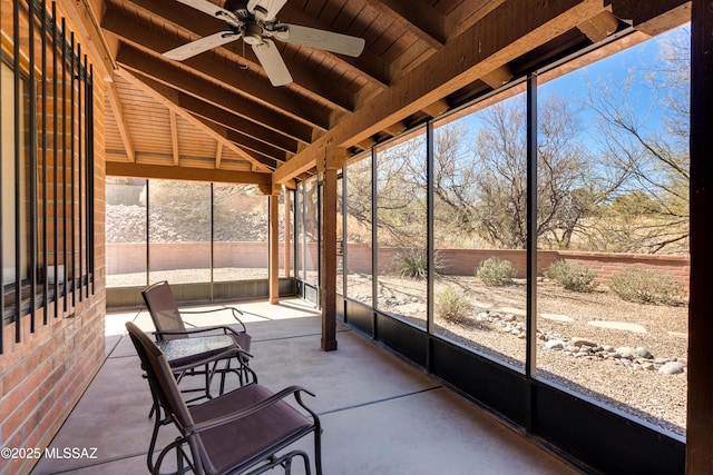 unfurnished sunroom featuring a ceiling fan, wood ceiling, and vaulted ceiling with beams