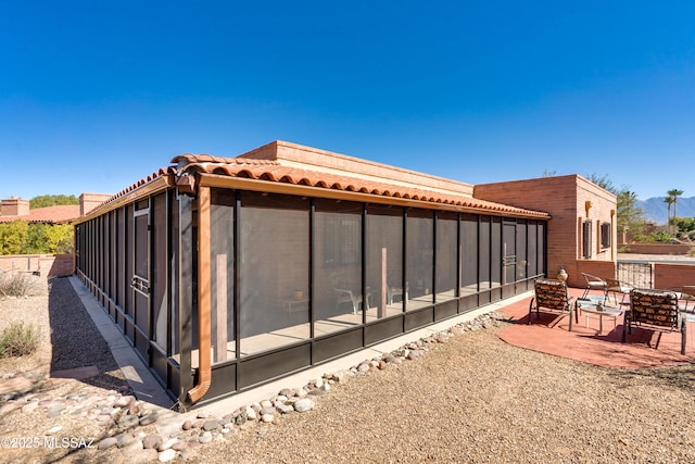 exterior space with a sunroom and a tiled roof