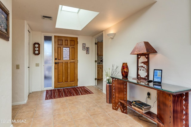 foyer with light tile patterned floors, a skylight, visible vents, and baseboards