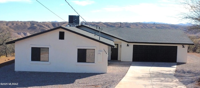 view of front of property with a mountain view, a garage, central AC, a shingled roof, and concrete driveway