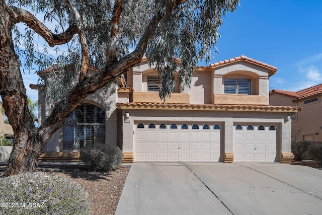 mediterranean / spanish-style house featuring concrete driveway, an attached garage, and stucco siding