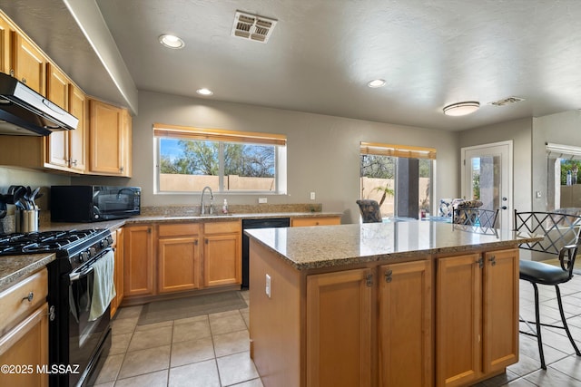 kitchen featuring visible vents, a kitchen island, a sink, under cabinet range hood, and black appliances