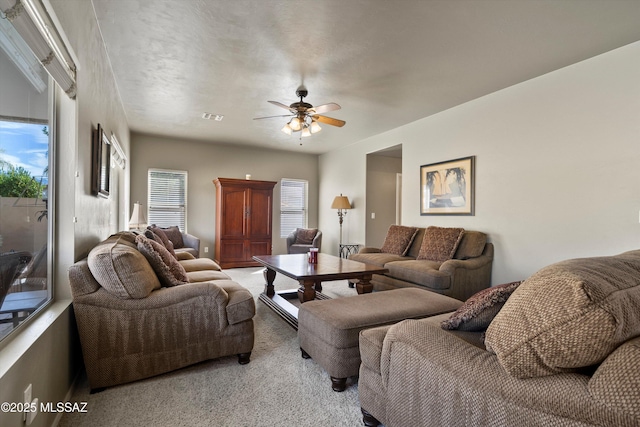 living room with a ceiling fan, visible vents, and carpet flooring