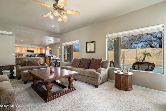 living area with light carpet, a ceiling fan, visible vents, and baseboards