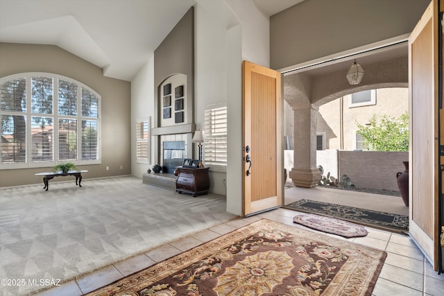 entrance foyer featuring a wealth of natural light, light colored carpet, a tiled fireplace, and light tile patterned floors