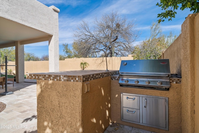 view of patio / terrace featuring a fenced backyard, a grill, and an outdoor kitchen