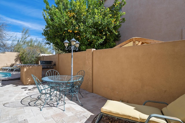 view of patio featuring exterior kitchen, grilling area, outdoor dining space, and fence