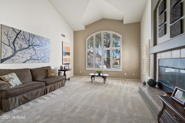 living area with light carpet, high vaulted ceiling, and a tiled fireplace