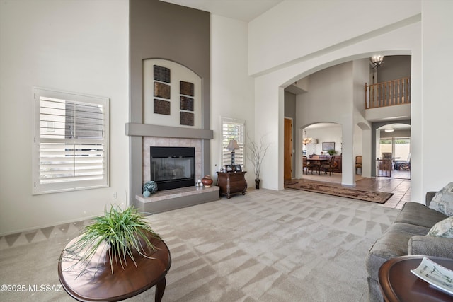 carpeted living room with a high ceiling, a tile fireplace, and a wealth of natural light