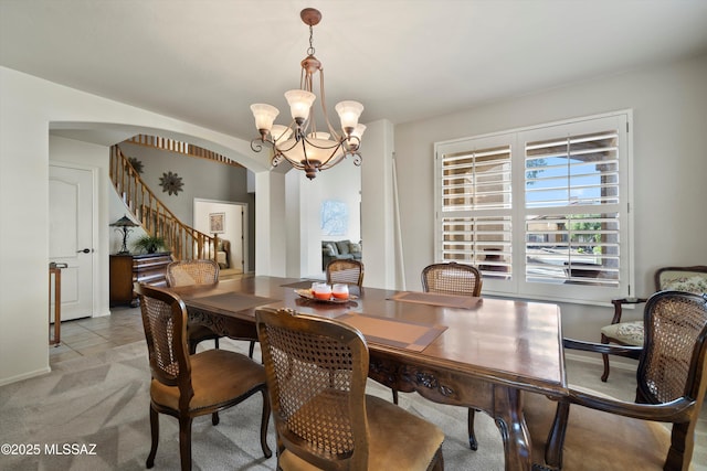 dining room featuring an inviting chandelier, stairs, arched walkways, and light colored carpet