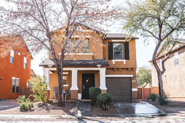 traditional-style house featuring a porch, an attached garage, fence, concrete driveway, and stucco siding