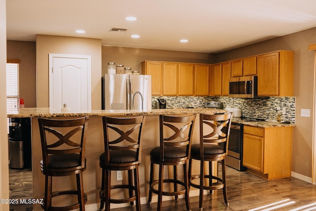 kitchen featuring visible vents, appliances with stainless steel finishes, decorative backsplash, and wood finished floors