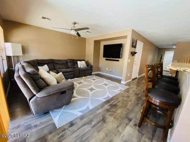 living room with a ceiling fan, wood finished floors, visible vents, and baseboards