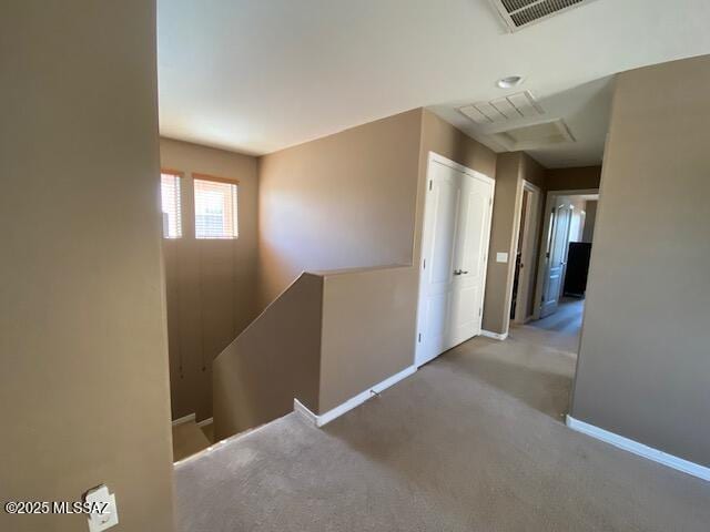 hall featuring carpet floors, baseboards, visible vents, and an upstairs landing