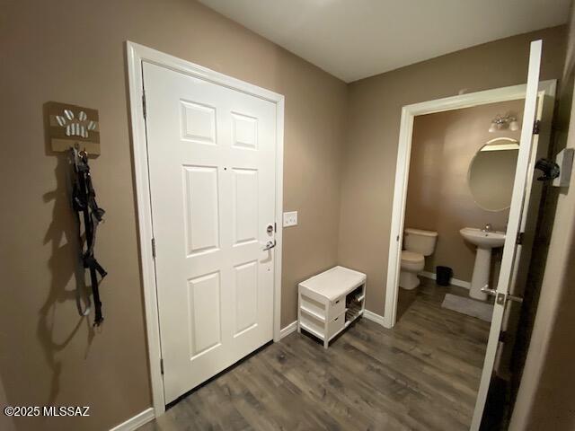 interior space with a sink, baseboards, and dark wood-type flooring