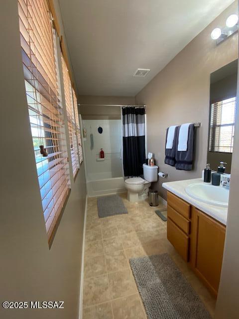 bathroom with tile patterned flooring, toilet, vanity, visible vents, and shower / bath combo with shower curtain