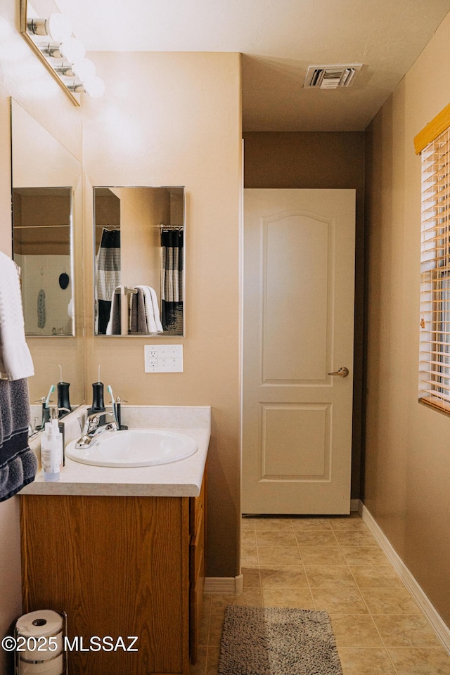 bathroom featuring tile patterned flooring, visible vents, vanity, and baseboards