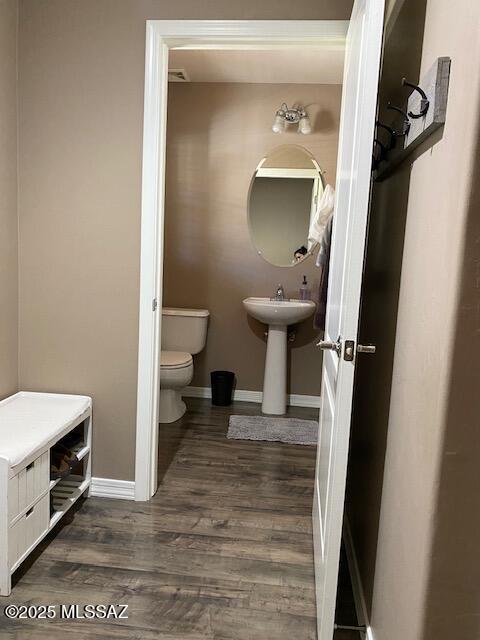 bathroom featuring baseboards, toilet, and wood finished floors