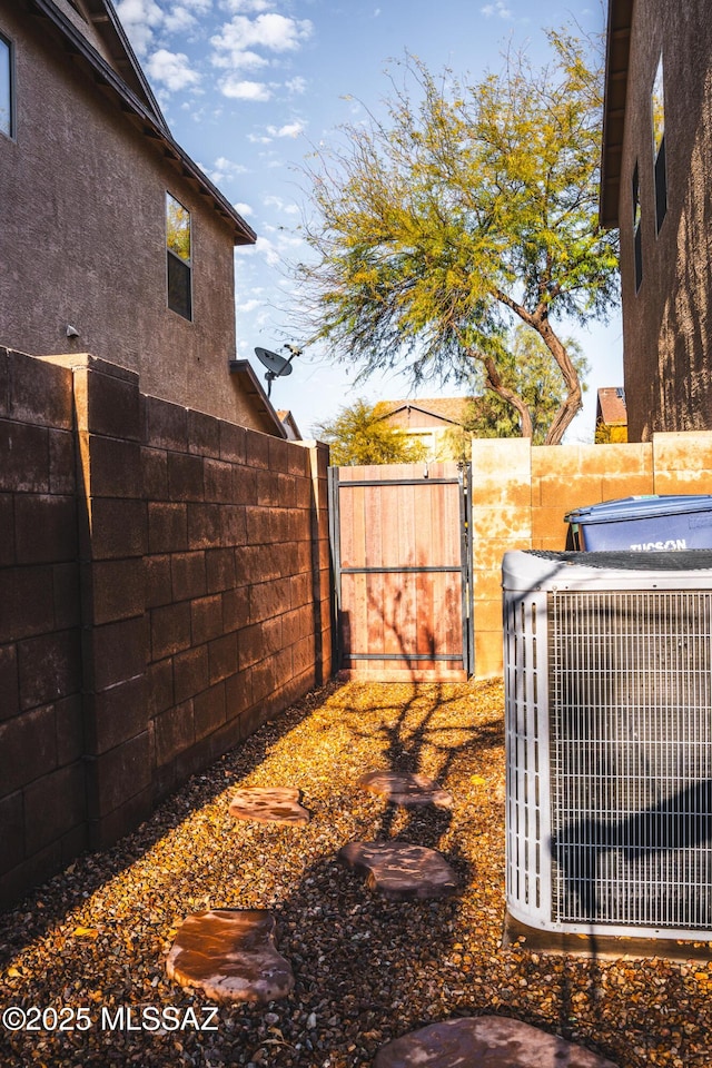 view of yard with a gate, central AC, and fence