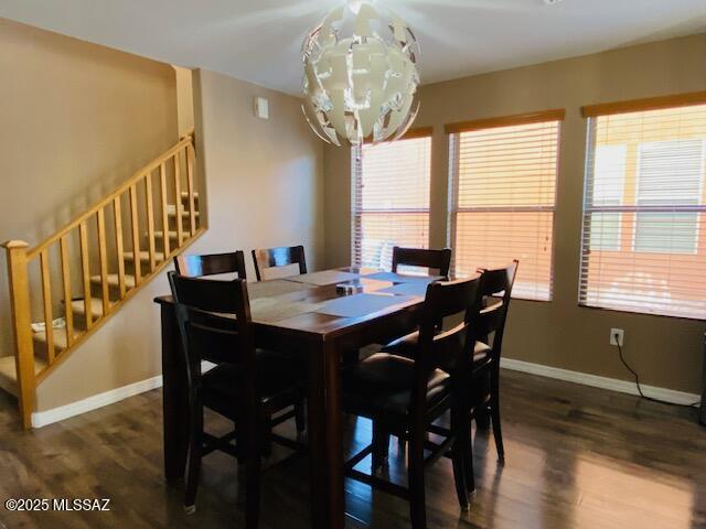 dining space featuring stairs, baseboards, a chandelier, and wood finished floors