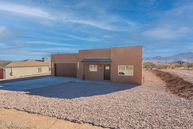 southwest-style home with a garage, concrete driveway, a tiled roof, a mountain view, and stucco siding