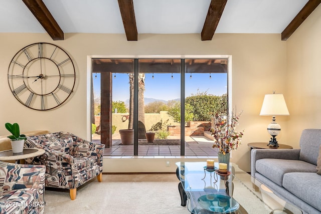 carpeted living area with beam ceiling