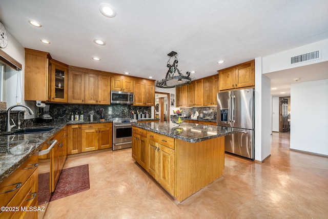 kitchen with a center island, brown cabinets, visible vents, appliances with stainless steel finishes, and a sink