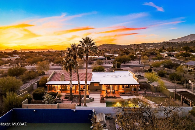 back of property at dusk featuring a fenced backyard, a mountain view, an outdoor hangout area, and a patio