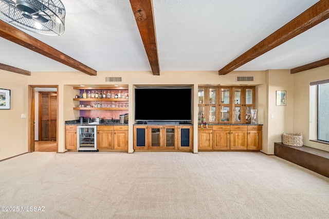 unfurnished living room featuring beverage cooler, light colored carpet, visible vents, and bar