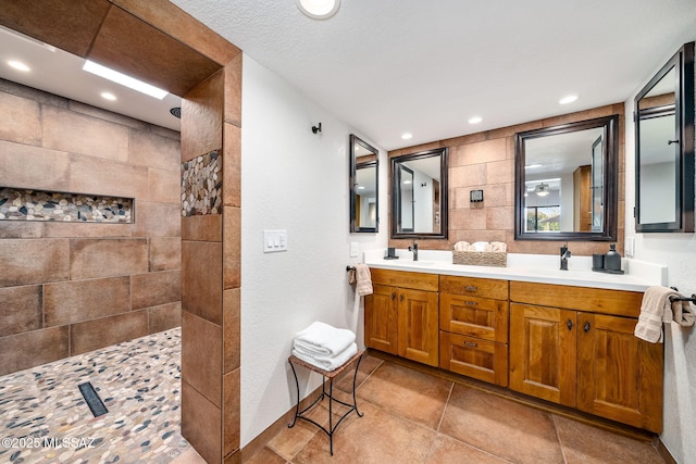 bathroom featuring double vanity, a walk in shower, a sink, and recessed lighting