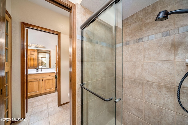 bathroom featuring a textured ceiling, tile patterned flooring, toilet, vanity, and a shower stall