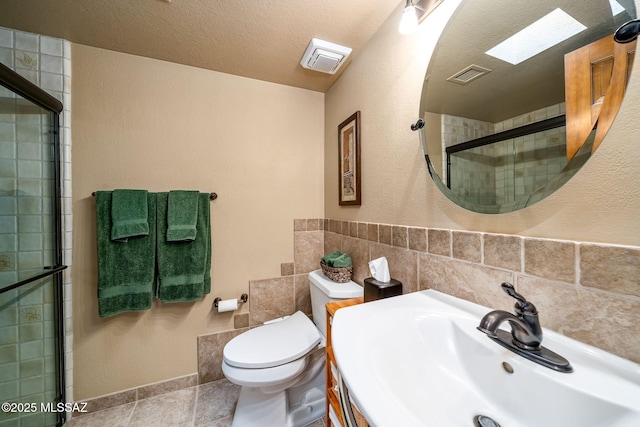 full bath featuring a stall shower, visible vents, toilet, a textured ceiling, and a sink