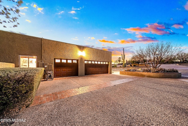 pueblo-style home with a garage, driveway, and stucco siding