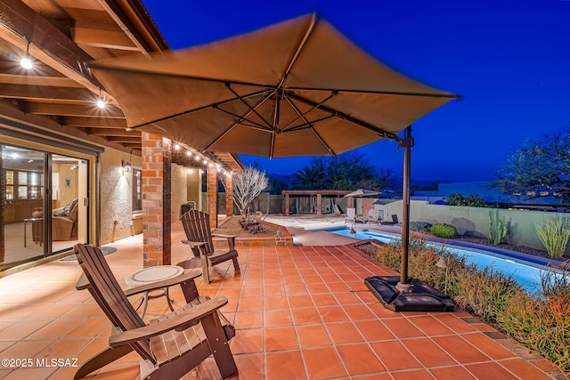 patio at night featuring a fenced backyard and a fenced in pool