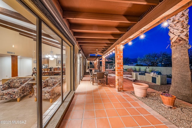 patio at night featuring visible vents, an outdoor kitchen, and outdoor dining space