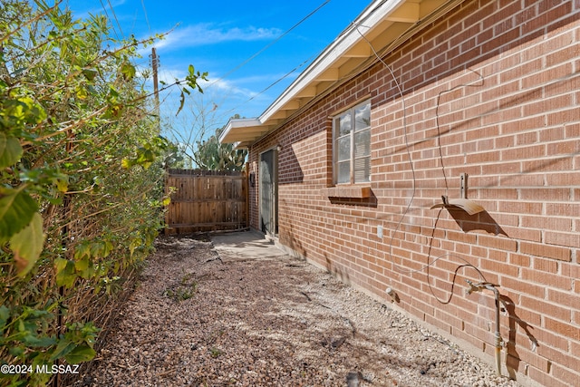 view of side of property with brick siding and fence