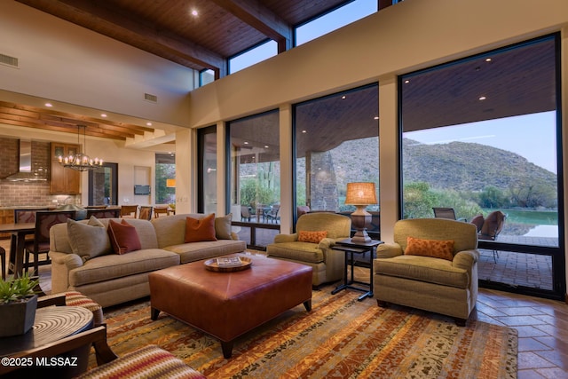 living room with a wealth of natural light, a mountain view, beam ceiling, and wooden ceiling