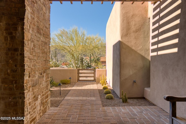 view of side of home featuring stucco siding, fence, a patio, and a gate