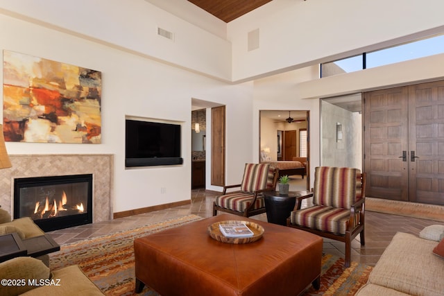 living room featuring visible vents, baseboards, a healthy amount of sunlight, and a glass covered fireplace