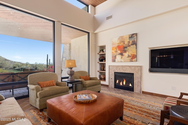 living room featuring built in shelves, a healthy amount of sunlight, visible vents, and a lit fireplace