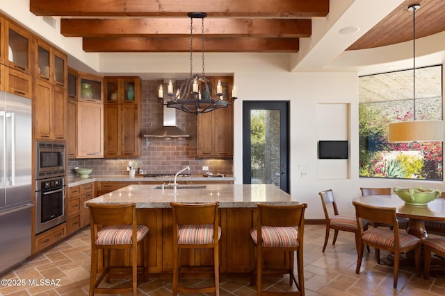 kitchen with beam ceiling, a sink, built in appliances, brown cabinets, and backsplash