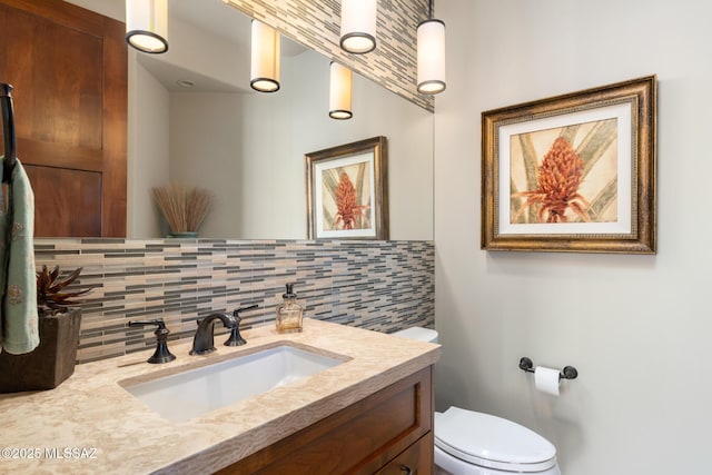 bathroom with vanity, toilet, and tasteful backsplash